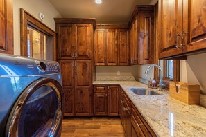 A kitchen with wooden cabinets, a built-in washing machine, granite countertops, and a sink. - One Sweet Getaway at Eagles Nest (Banner Elk)