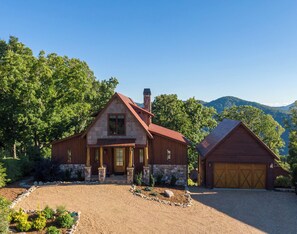 A two-story stone house with a red roof, a chimney, and a garage. - One Sweet Getaway at Eagles Nest (Banner Elk)