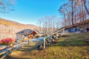 Uma cabana com varanda, escadaria e vista da floresta ao redor.