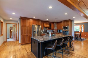 A spacious kitchen with wooden cabinets, stainless steel appliances, and a large island with bar stools.
