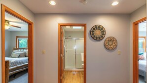 A hallway with wooden flooring, a glass shower door, and two decorative wall plates. - Boulder Sky at River Run (Banner Elk)