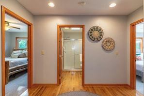 A hallway with wooden flooring, a glass shower door, and two decorative wall plates. - Boulder Sky at River Run (Banner Elk)