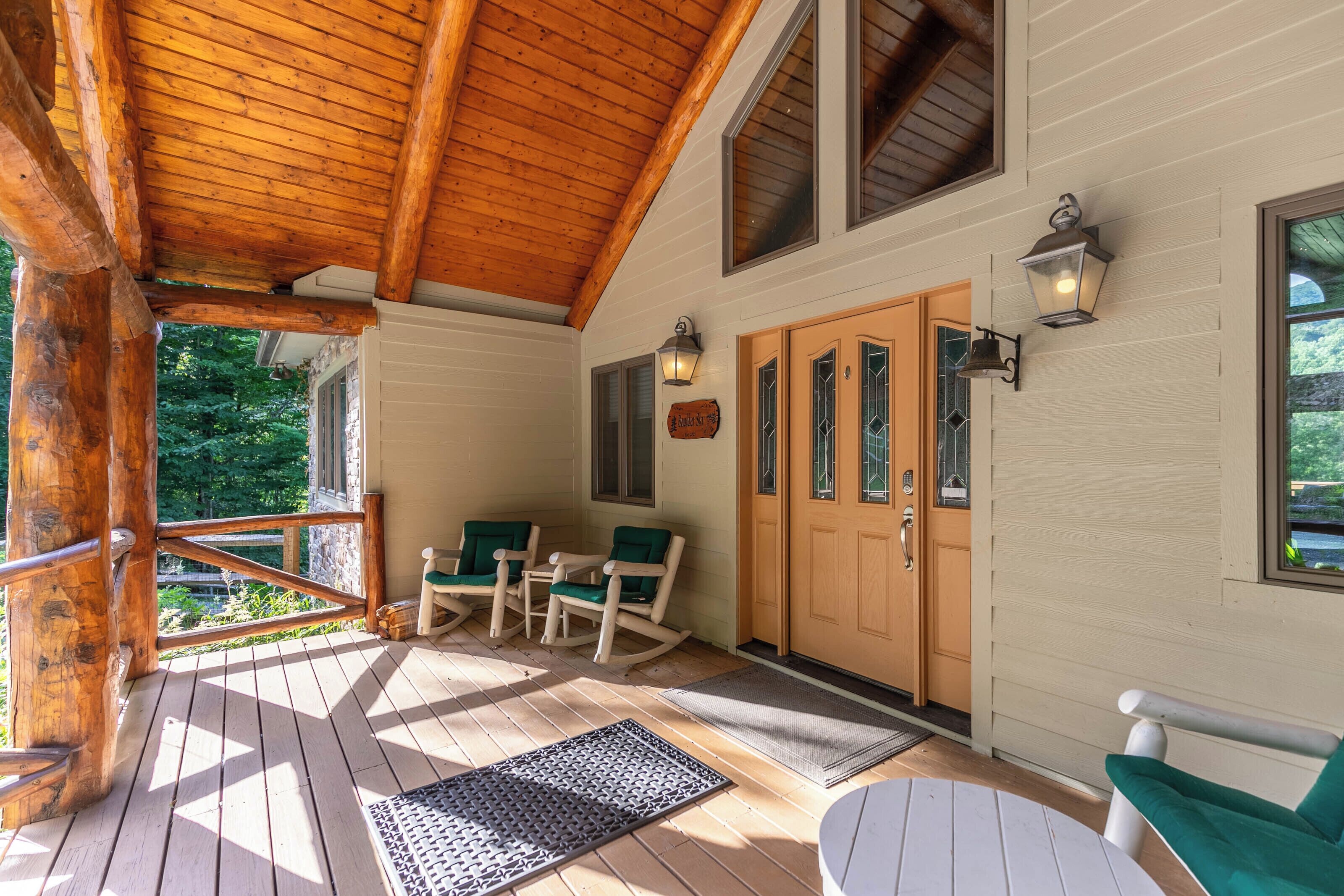 A wooden deck with a covered area, a door with glass panels, and a seating arrangement with chairs.