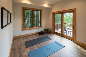 Une pièce spacieuse dotée d’un plancher en bois, de grandes fenêtres et d’une porte-fenêtre coulissante donnant sur une terrasse extérieure.