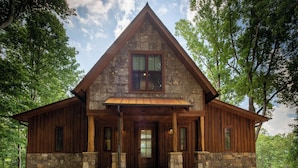 A rustic cabin with a stone foundation, wooden walls, and a gabled roof. - Mountain Vistas at Eagles Nest (Banner Elk)