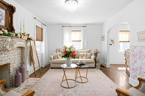 Ein Wohnzimmer mit Kamin, einer Couch, einem Couchtisch und einer Deckenleuchte.