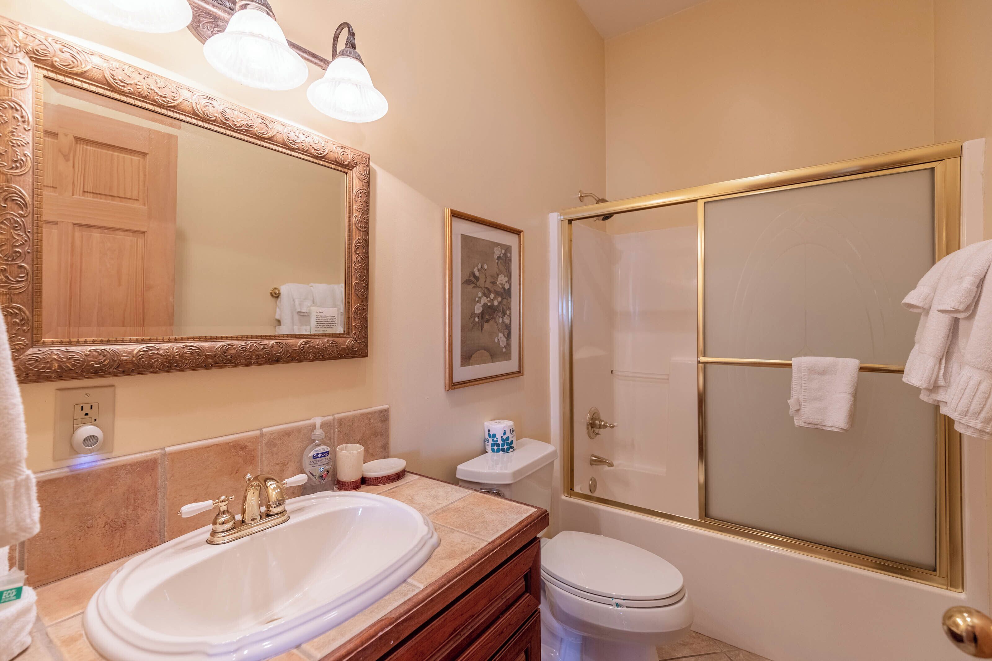 A bathroom with a large mirror, a bathtub, a toilet, and a shower area.