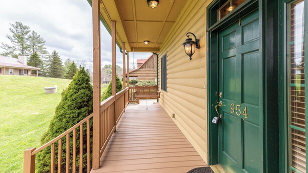 A wooden porch with a green door marked "954", a bench, and a view of a house in the background. - Buena Vista (Fleetwood)