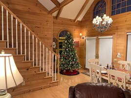 Un interior de madera con una escalera, un árbol de Navidad y un comedor.