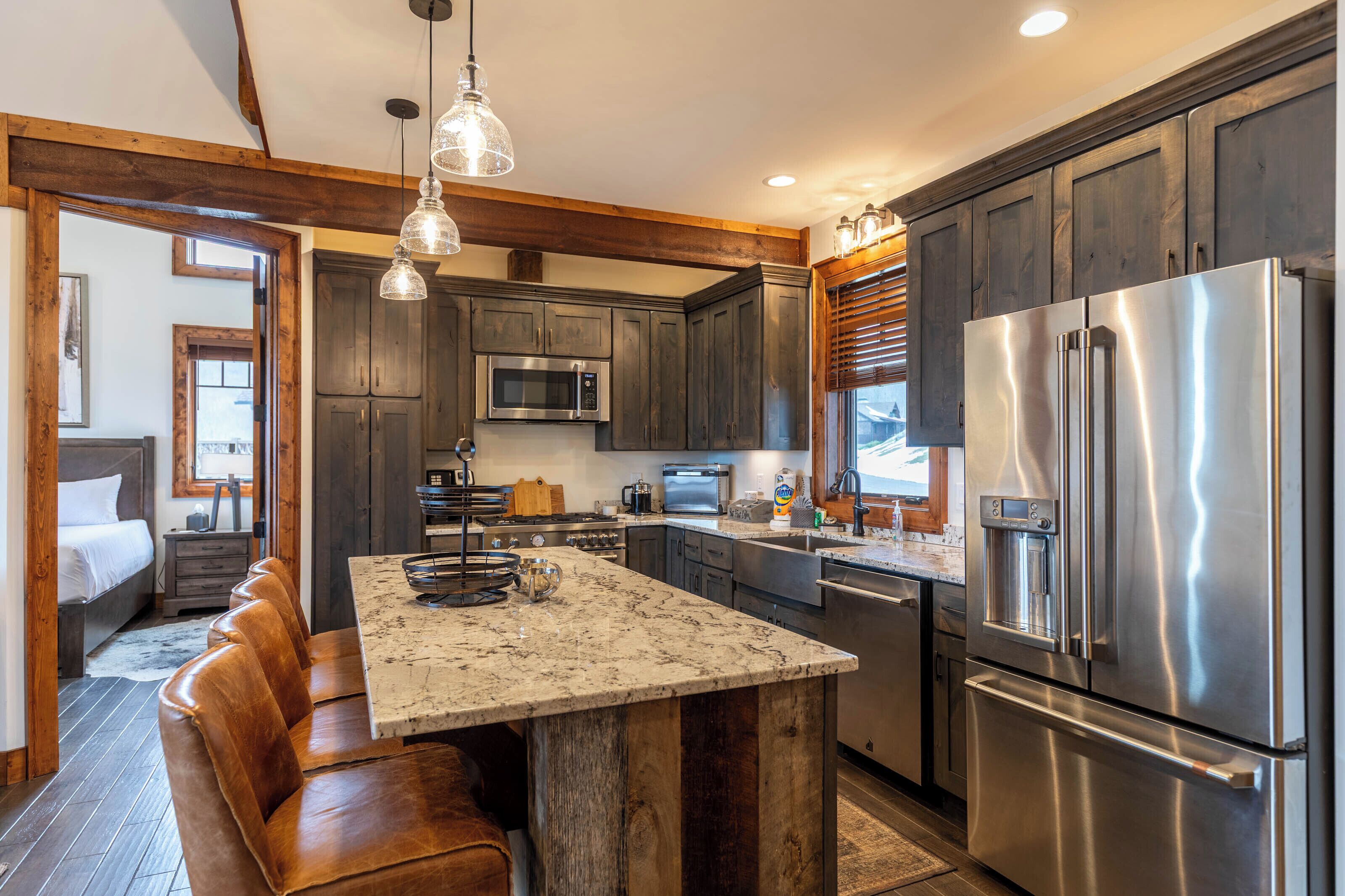 A modern kitchen with dark wood cabinets, stainless steel appliances, and a central island with seating.