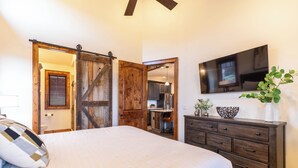 Ein Schlafzimmer mit einem Bett, einem Schminktisch, einem Fernseher und einer Schiebetür im Stil einer Scheune.