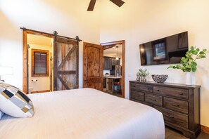 A bedroom with a bed, a dresser, a television, and a sliding barn door. - True Blue 92 at Eagles Nest (Banner Elk)