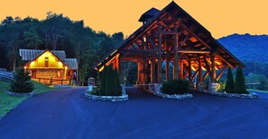 A wooden cabin with a sloped roof and a stone foundation, surrounded by a stone wall and small trees. - True Blue 92 at Eagles Nest (Banner Elk)
