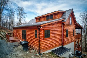 Eine Blockhütte mit steilem Dach, einer Veranda und einer kleinen Terrasse.