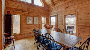 A wooden cabin interior with a dining table, chairs, and artwork on the walls. - High Time Cabin (Banner Elk)