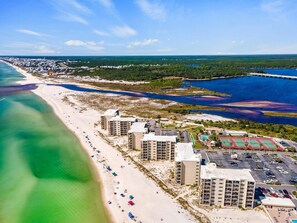 An aerial view of a coastal hotel with multiple buildings, a beach, and a marina.