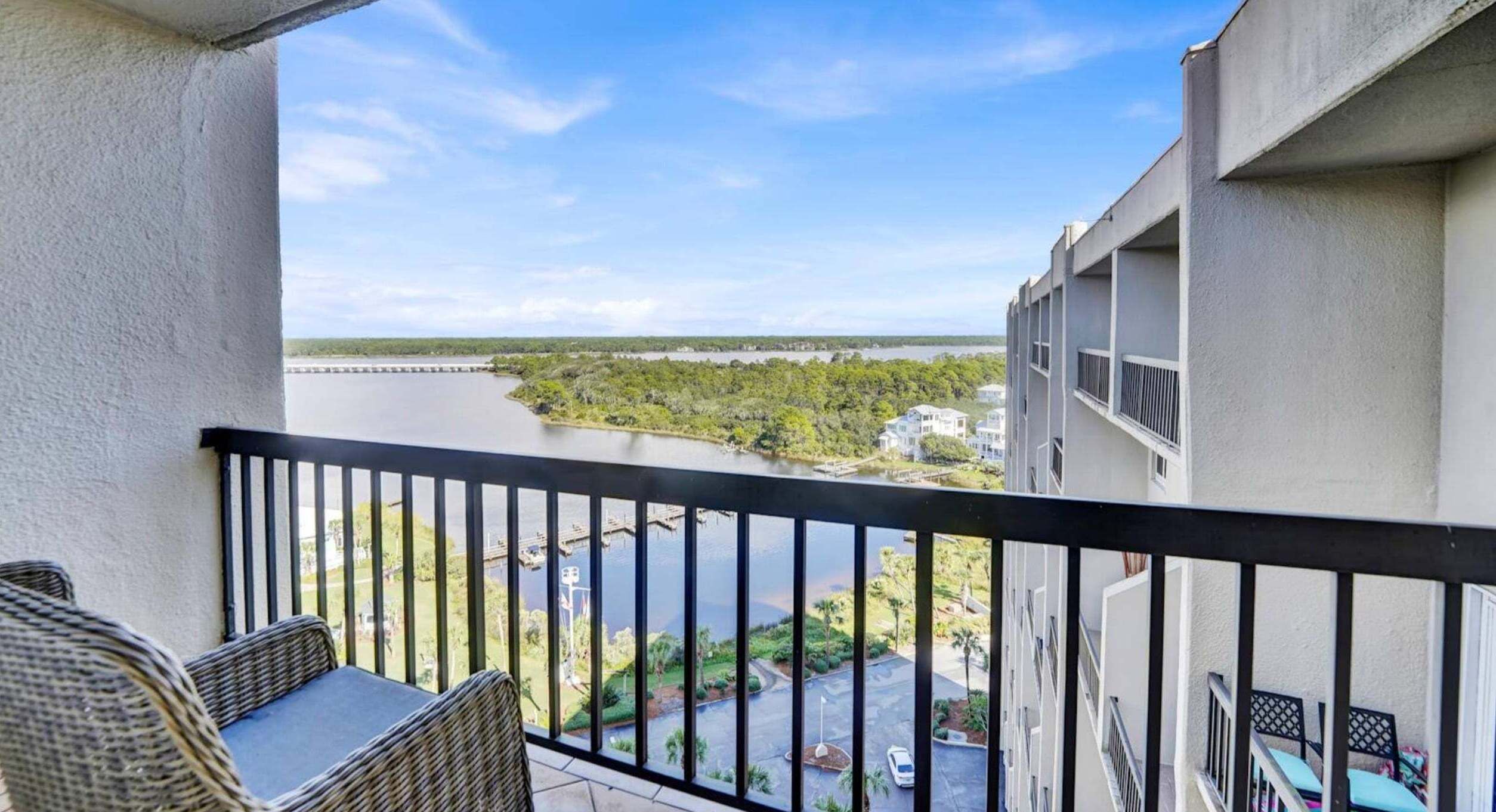A balcony with wicker furniture, a view of a river, and a bridge.