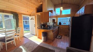 A wooden interior with a kitchen, dining area, and a view of the outside.