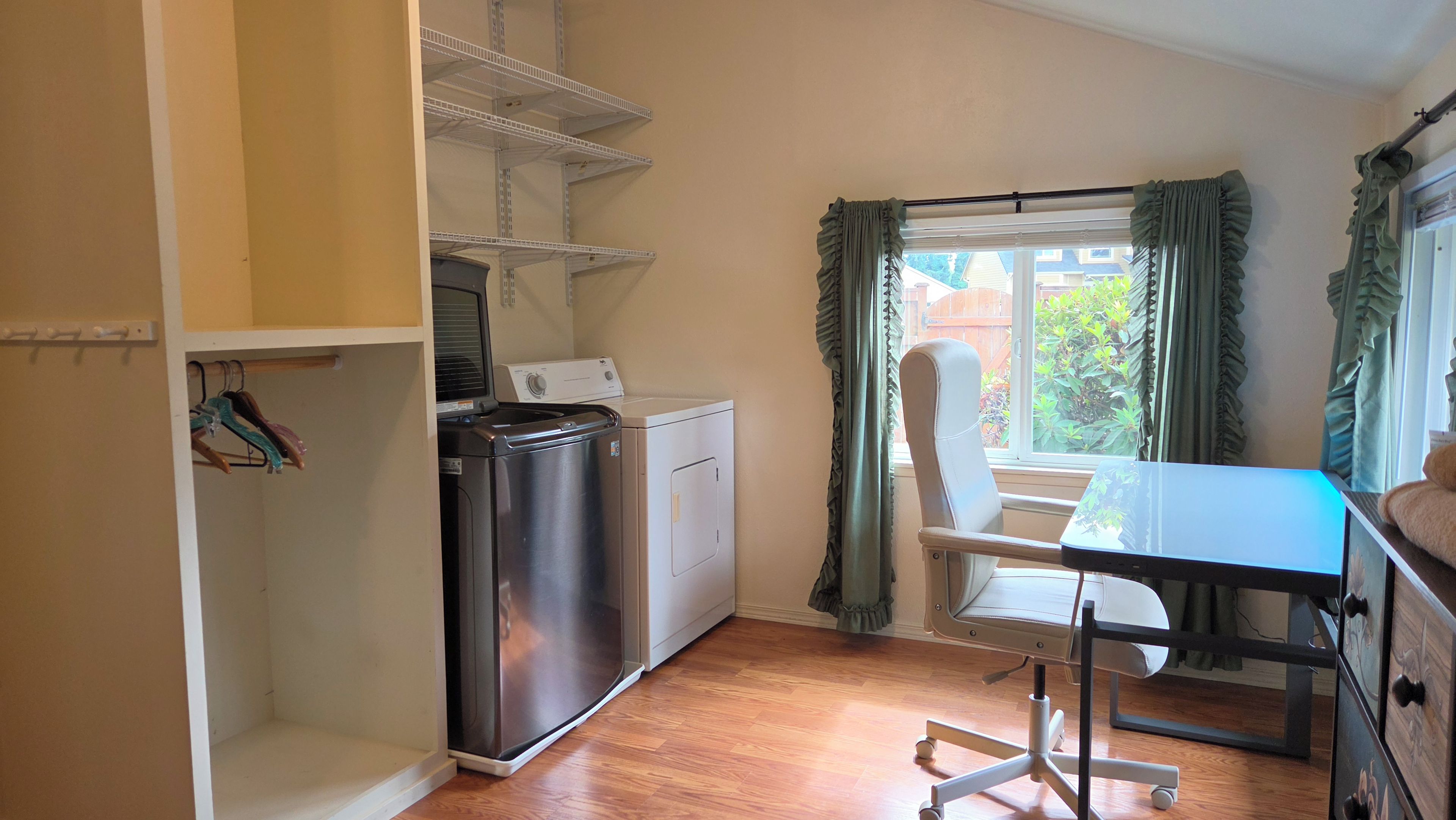 Une cuisine compacte équipée d’un lave-linge, d’une petite table et d’une chaise.