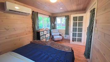 Une pièce comprenant un lit, une commode, une chaise et une porte donnant sur l’extérieur.