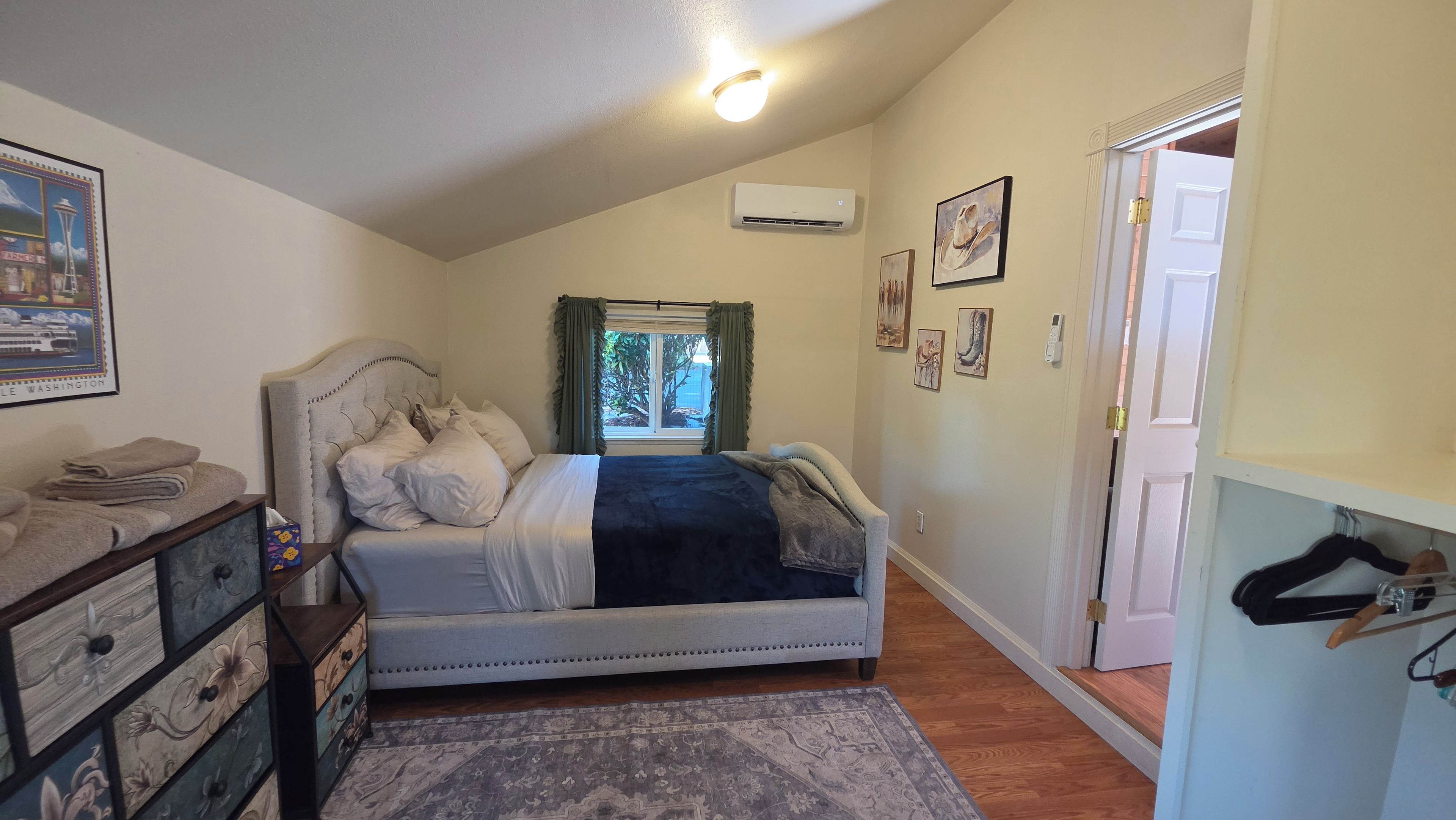 A bedroom with a bed, a dresser, a rug, and a door leading to another room.