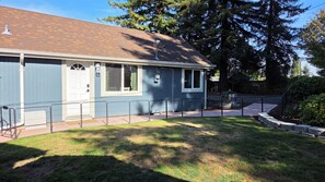 A single-story building with a front door, windows, and a small porch area. - Cozy 2-bedroom cottage with AC in a quiet, charming Puyallup neighborhood. (Puyallup)