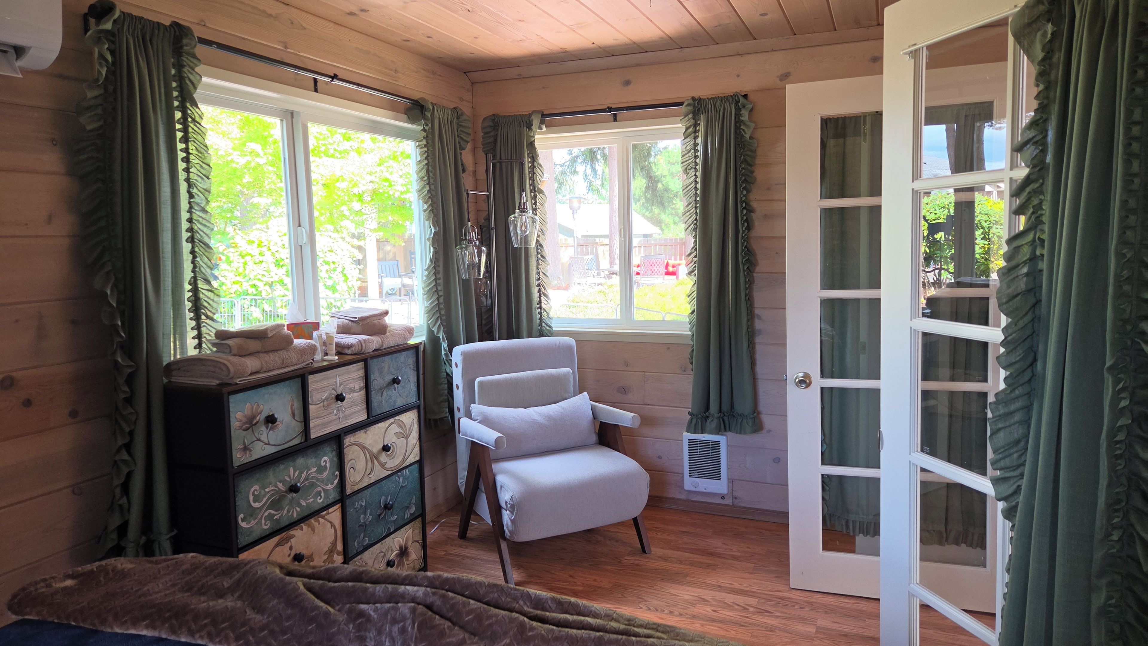 Une pièce avec un intérieur en bois, une chaise blanche, une commode et une porte donnant sur l’extérieur.