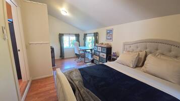 A bedroom with a bed, a desk, and a chair.