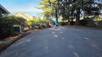 A residential street with houses, trees, and a patio area with outdoor furniture.