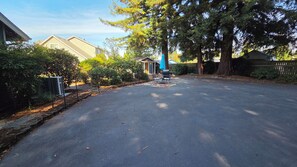 A residential street with houses, trees, and a patio area with outdoor furniture. - Cozy 2-bedroom cottage with AC in a quiet, charming Puyallup neighborhood. (Puyallup)