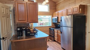 A kitchen with wooden cabinets, a stainless steel refrigerator, a microwave, and a coffee maker.