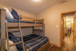 A bunk bed room with a wooden ladder, a single bed below, and a door leading to a hallway. - Cozy Cottage (Blowing Rock)