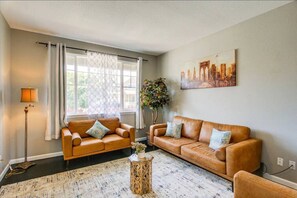 A living room with two leather sofas, a floor lamp, a side table with a plant, and a painting on the wall.