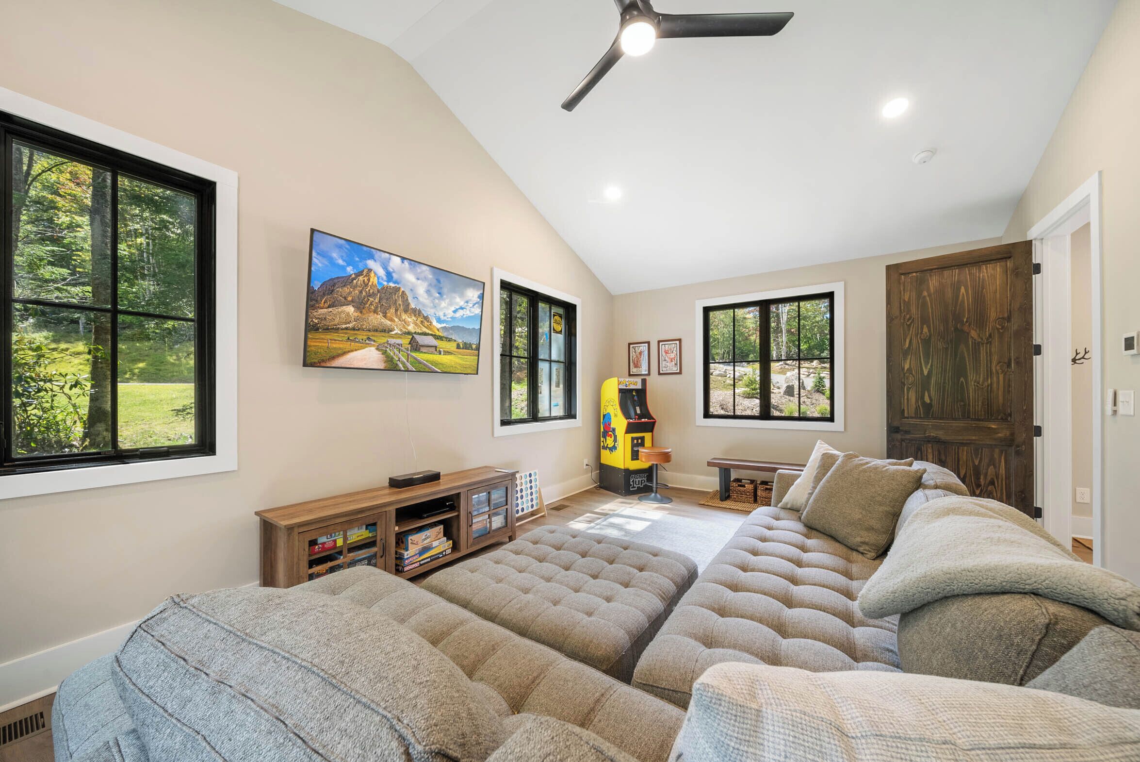 A spacious living room with a large sectional sofa, a ceiling fan, and a view of a mountain landscape through the windows.