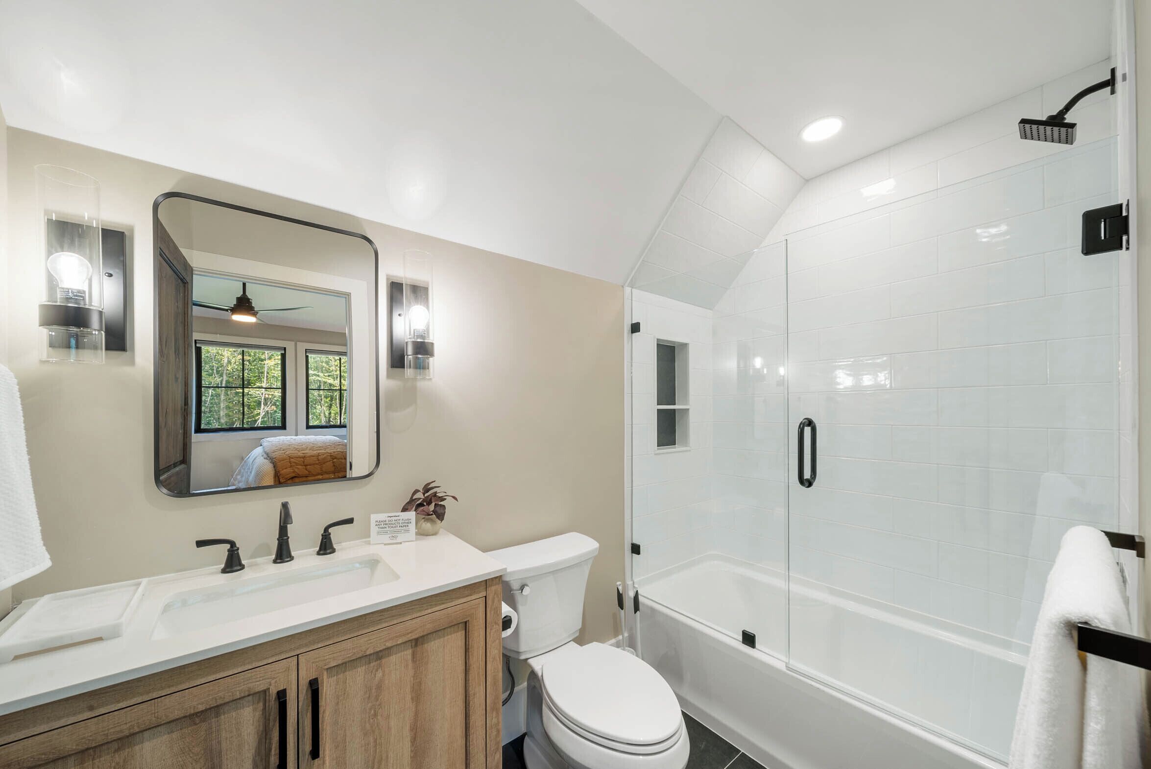 A bathroom with a white sink, mirror, toilet, and a walk-in shower.