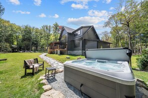 Een huis met een hottub, een pad van stenen en buitenmeubilair.