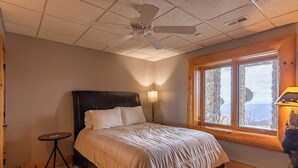A bedroom with a bed, a standing lamp, a ceiling fan, and a window with a view. - Good Day Sunshine (Lenoir)