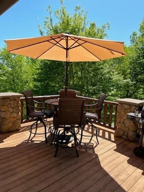 Un patio al aire libre con una mesa y sillas de madera, una sombrilla y paredes de piedra.