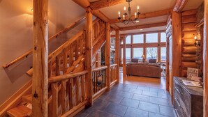 A wooden staircase with a chandelier, a stone fireplace, and a cozy seating area with a view. - Good Day Sunshine (Lenoir)