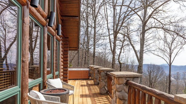 A wooden deck with stone railings, wicker chairs, and a hot tub. - Good Day Sunshine (Lenoir)