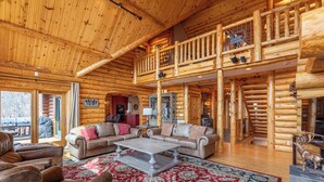 A spacious log cabin interior with a large living area, a second-floor balcony, and a rustic decor. - Good Day Sunshine (Lenoir)