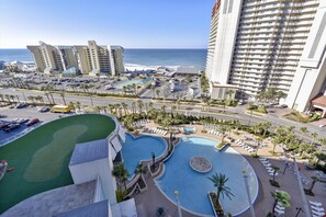 Ein Resort mit mehreren Schwimmbecken, einem Parkplatz und Meerblick.