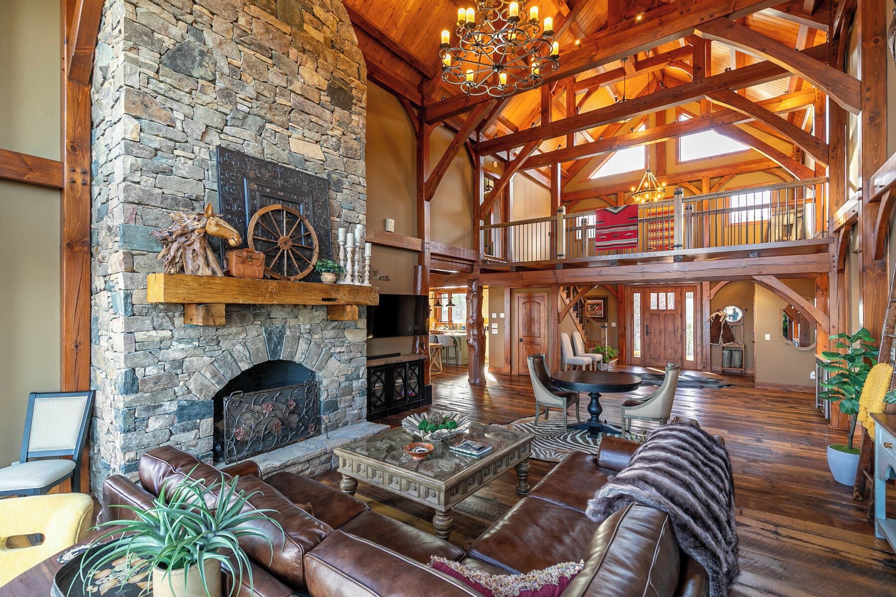 A spacious interior with a stone fireplace, leather seating, and a high wooden ceiling.