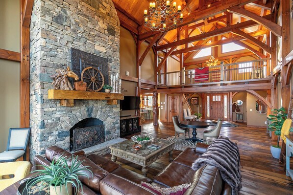 A spacious interior with a stone fireplace, leather seating, and a high wooden ceiling.