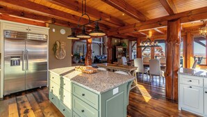 Eine großzügige Küche mit Granit Arbeitsplatten, einem Edelstahlkühlschrank und einem Essbereich mit Holztisch und Stühlen.