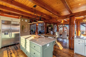 A spacious kitchen with granite countertops, a stainless steel refrigerator, and a dining area with a wooden table and chairs. - Bailey's Creek Lodge (Hudson)
