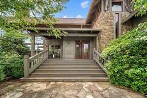 A stone building with a wooden staircase leading to a door marked with the number 85. - Overlook at Wilderness Trail (Linville)