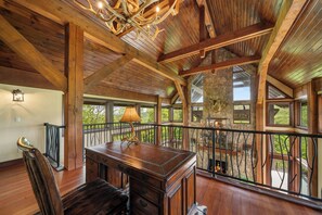 A spacious room with a wooden ceiling, a large desk, and a view of the outdoors through large windows. - Overlook at Wilderness Trail (Linville)