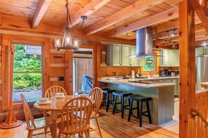 Ein Holzblockhaus-Interieur mit Essbereich, Küche und Bar.