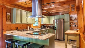 A kitchen with a central island, bar stools, a refrigerator, and a microwave. - Lakeview (Vilas)